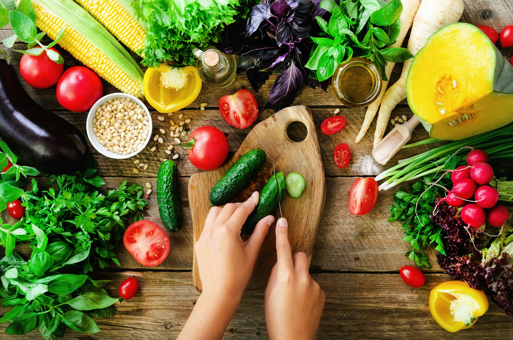 Woman hands cutting vegetables on wooden background. Vegetables cooking ingredients, top view, copy